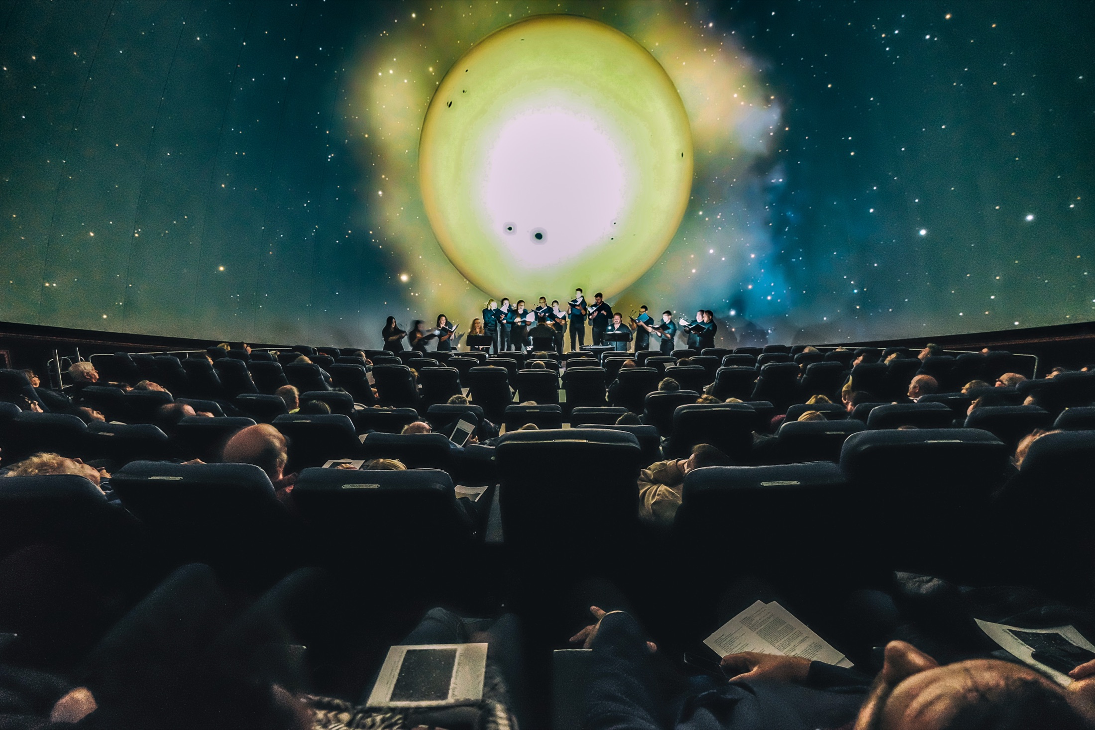 Choir performing beneath a planetarium projection