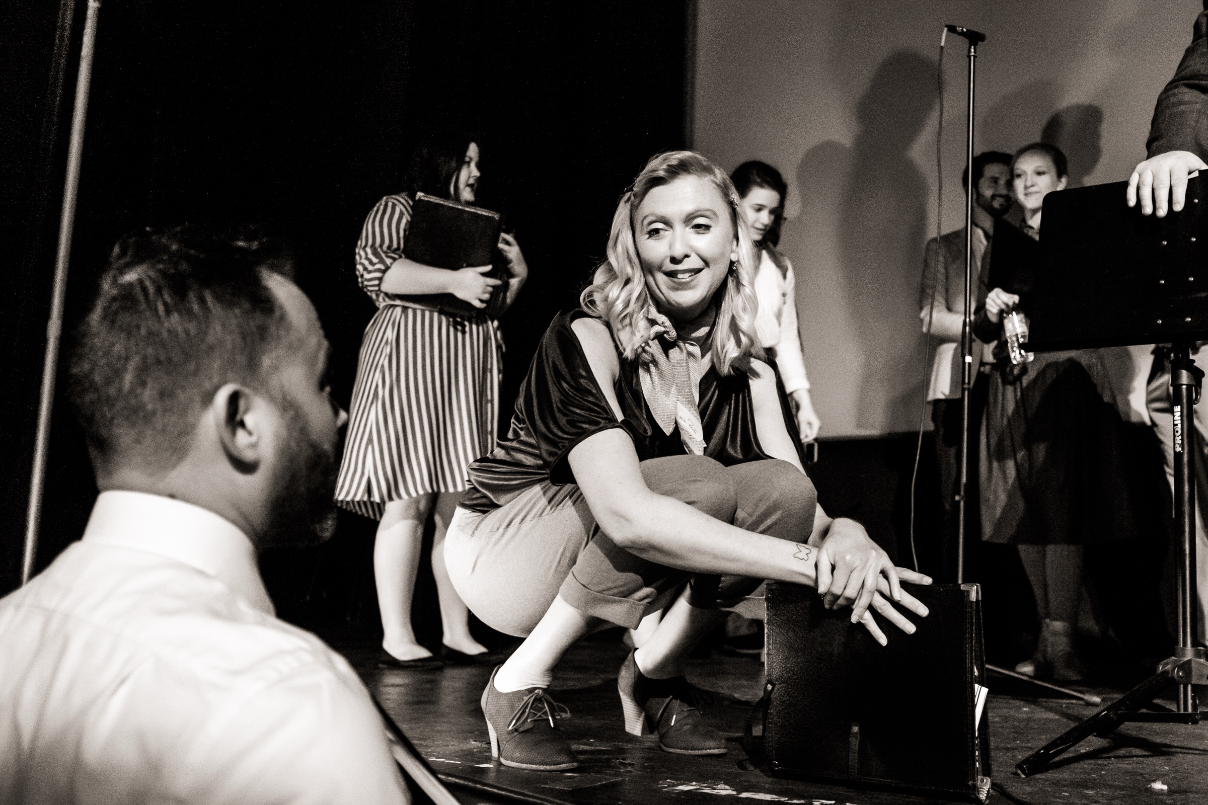 Betty's Notebook performer seated among singers and music stands