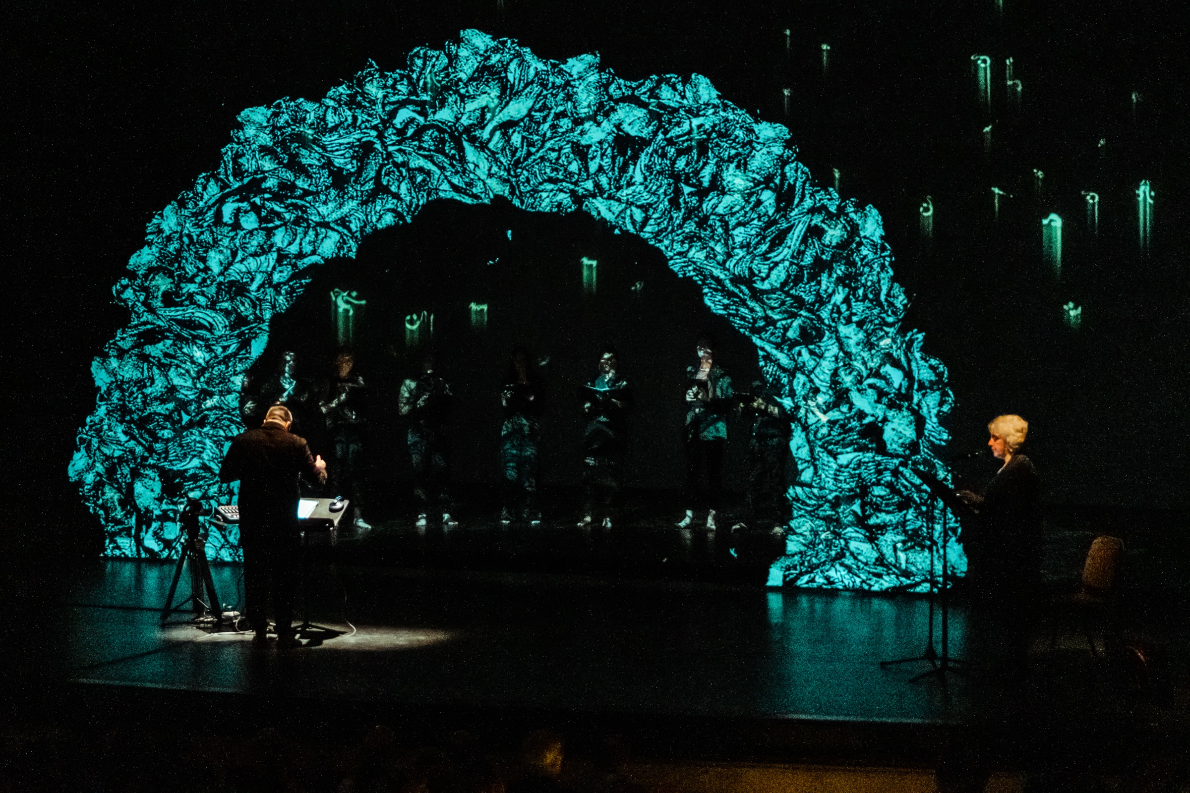 Dark SHAMS stage image with teal projection and singer at the edge of the stage